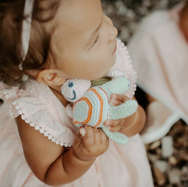 Child holding a knitted toy with a blurred natural background