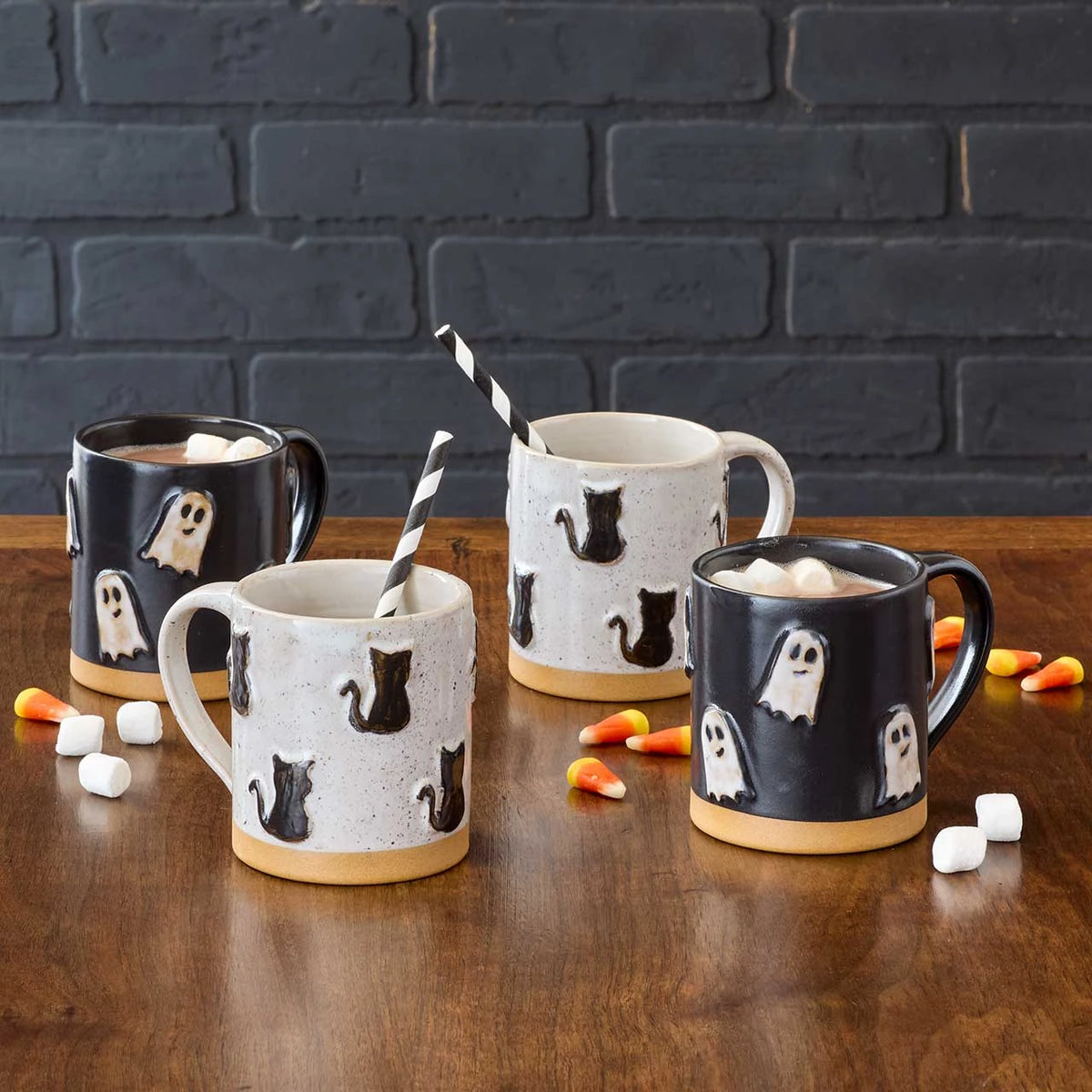 ghost mgs and black cat mugs on a wooden surface with candy corn