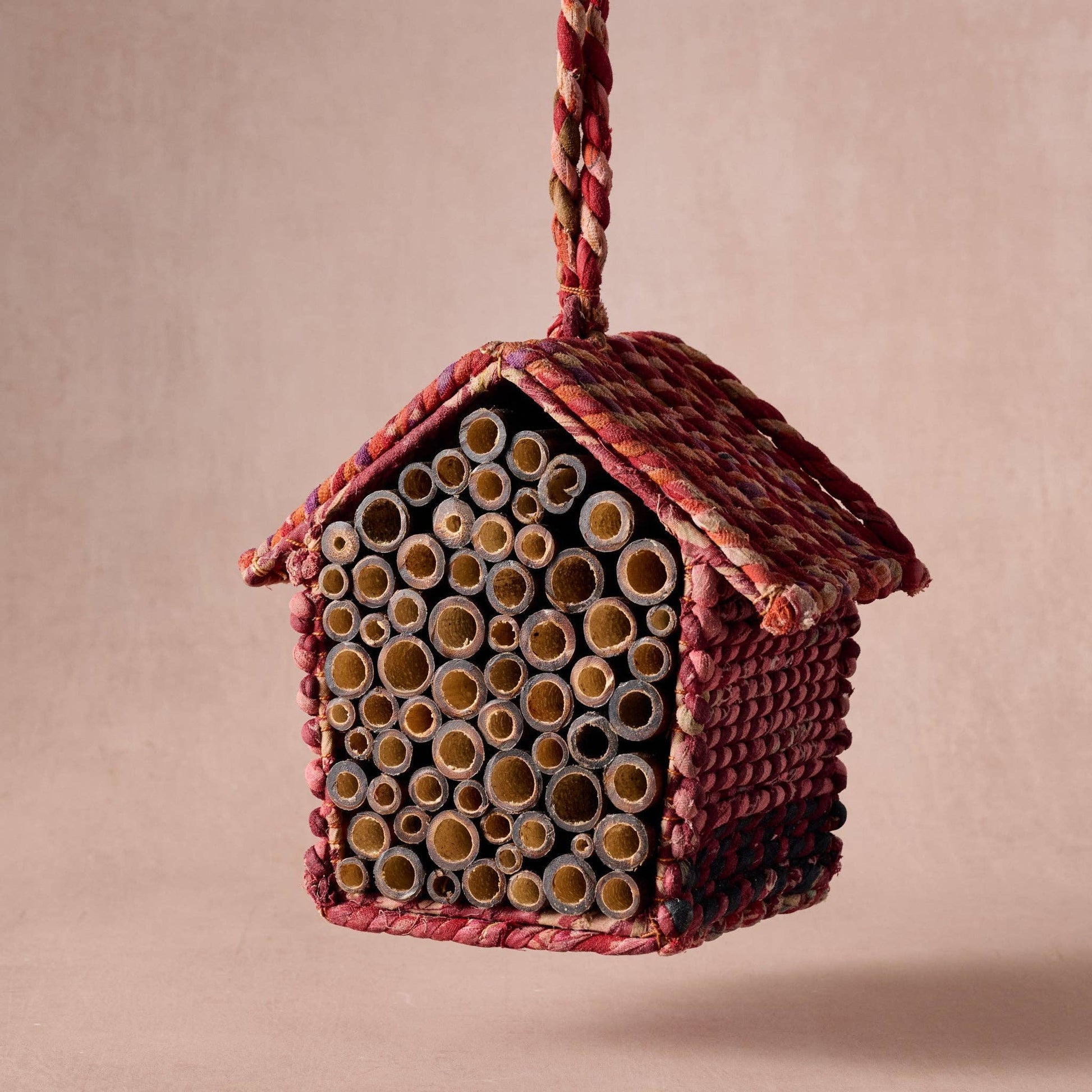 Woven birdhouse with natural materials on a beige background