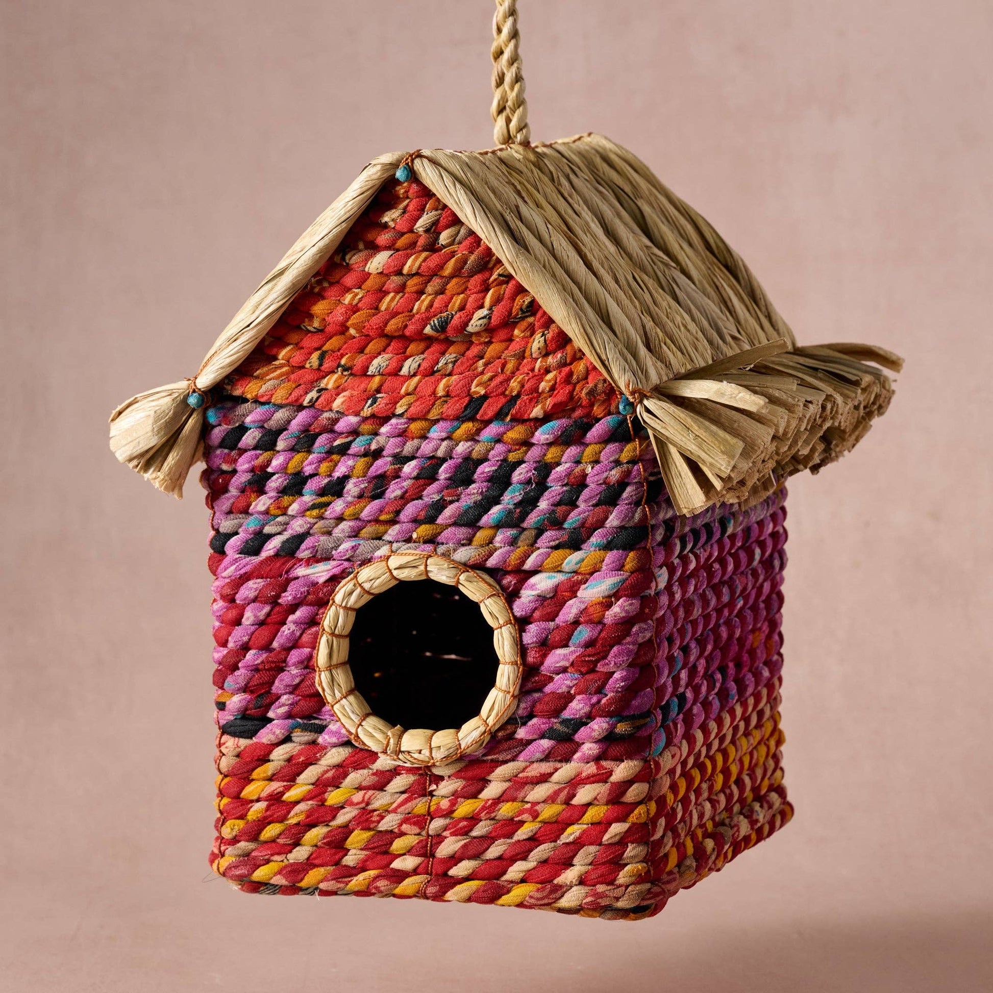 Colorful woven birdhouse with a plain background