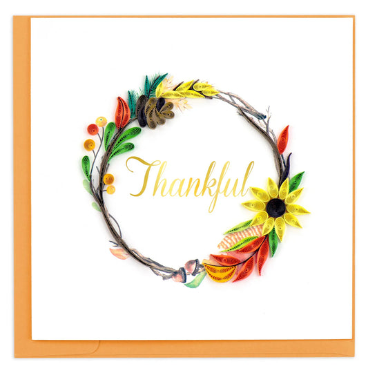 Decorative wreath with colorful flowers and leaves and the word 'Thankful' on a white background.