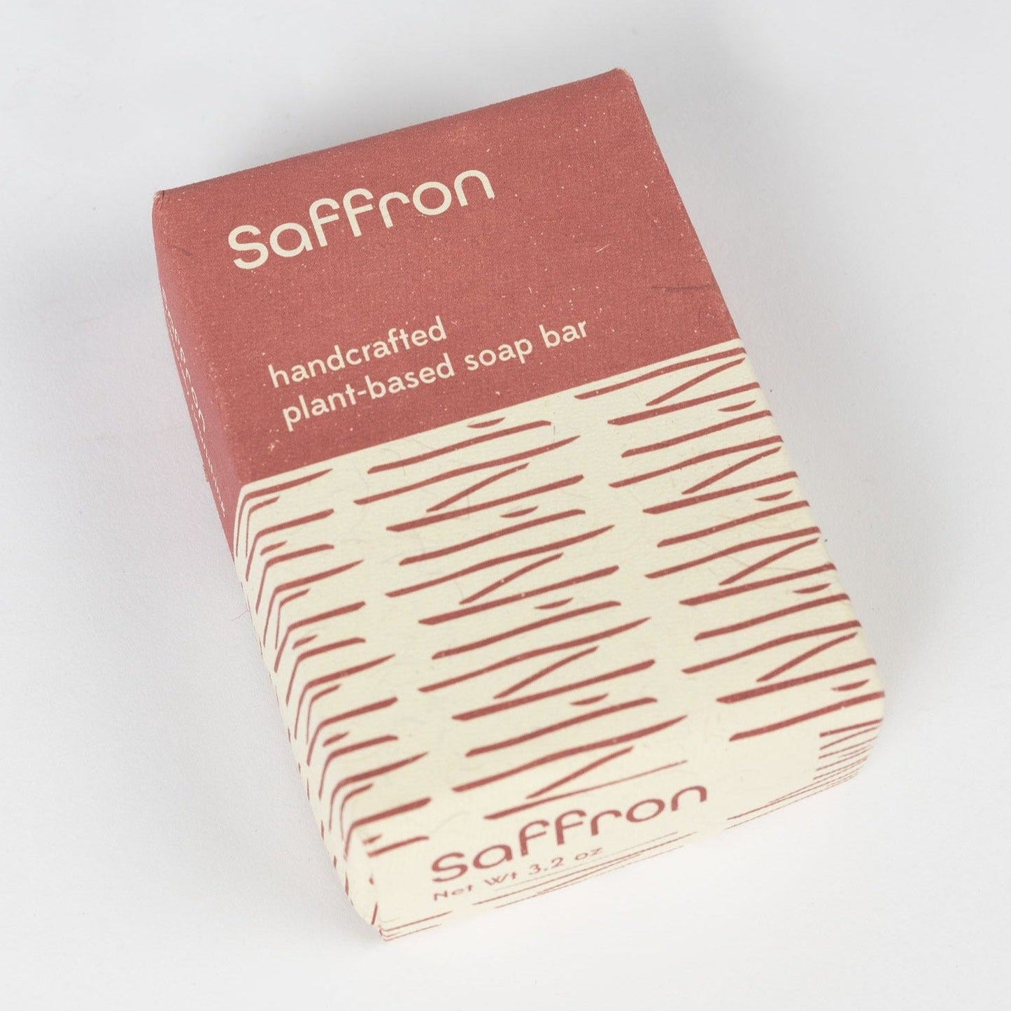 A red and tan geometric package that says "Saffron" is laid on a pain white background.