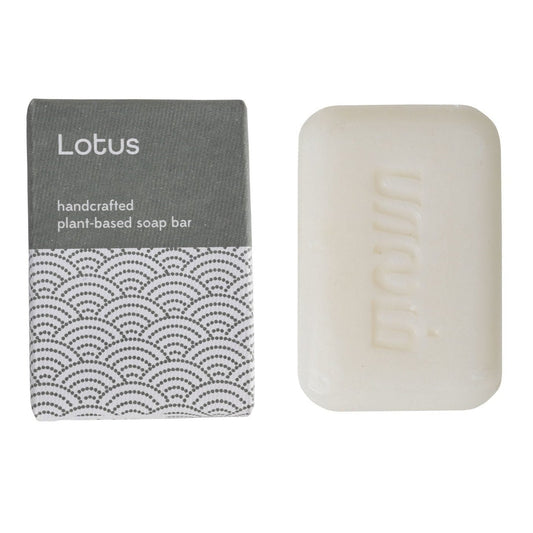 A bar of soap and blue and white package with a label that reads 'LOTUS Handcrafted Plant Based Soap Bar.'