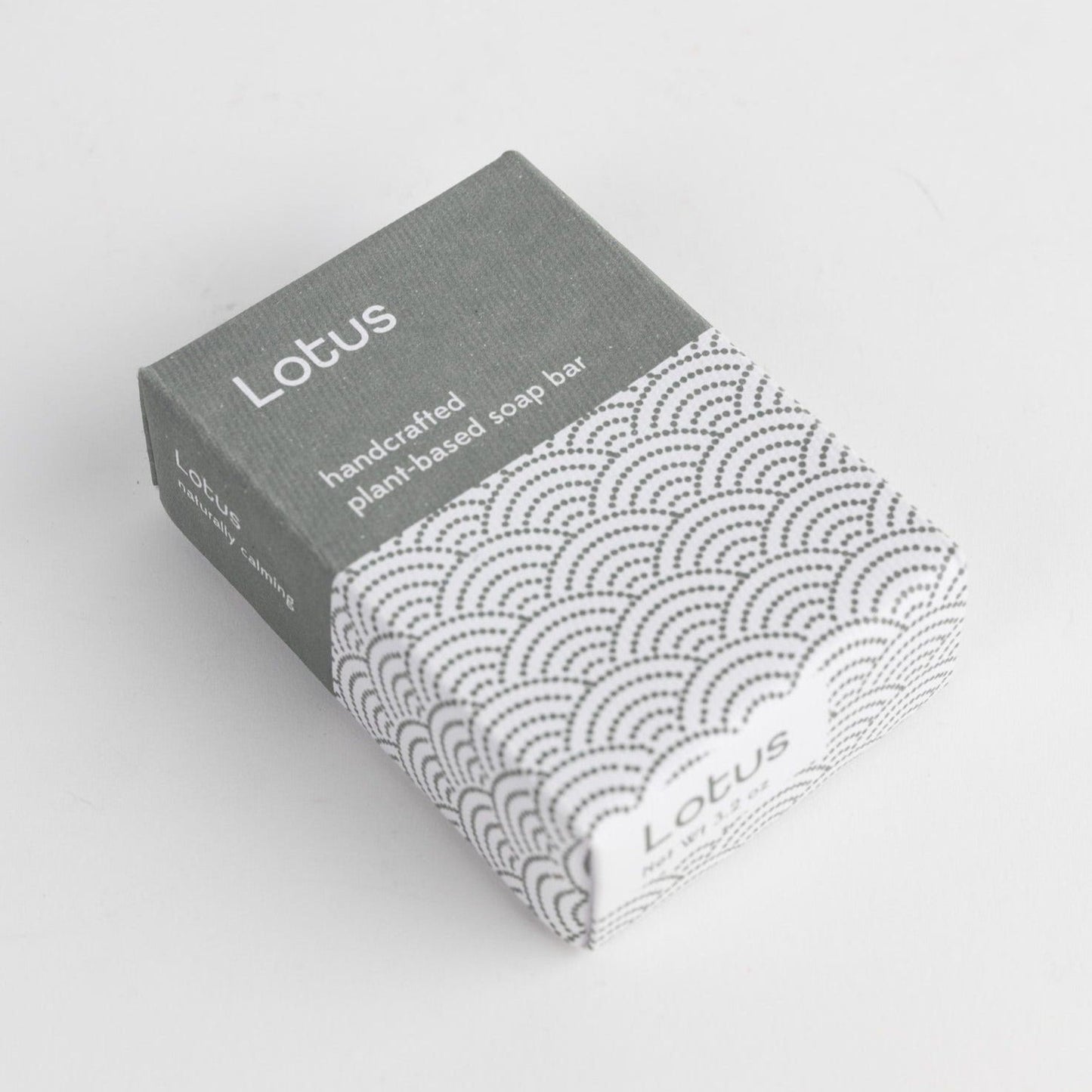 A blue and white rectangular package is shown on a white background with the words "Lotus" and "handcrafted plant-based soap bar."