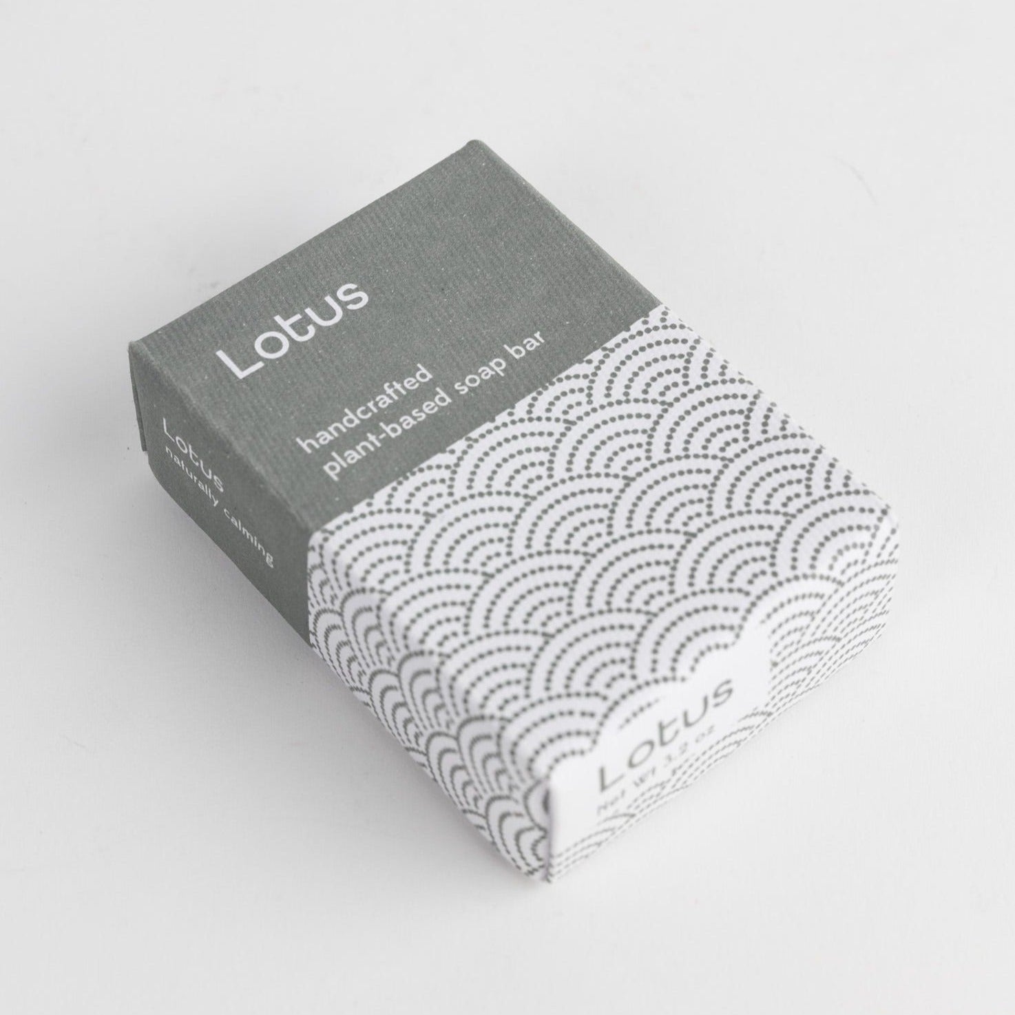 A blue and white rectangular package is shown on a white background with the words "Lotus" and "handcrafted plant-based soap bar."