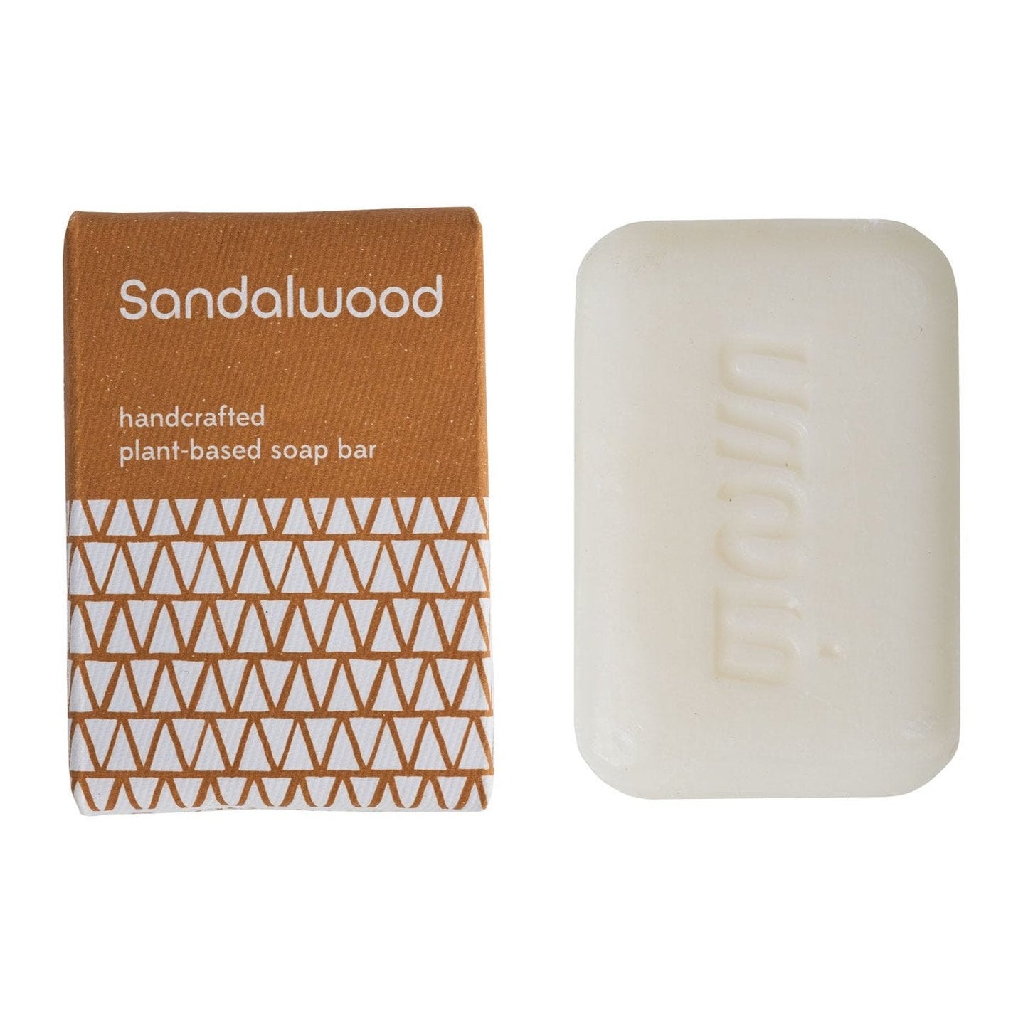 A bar of handcrafted sandalwood soap next to its packaging, which has a geometric pattern in brown and white.