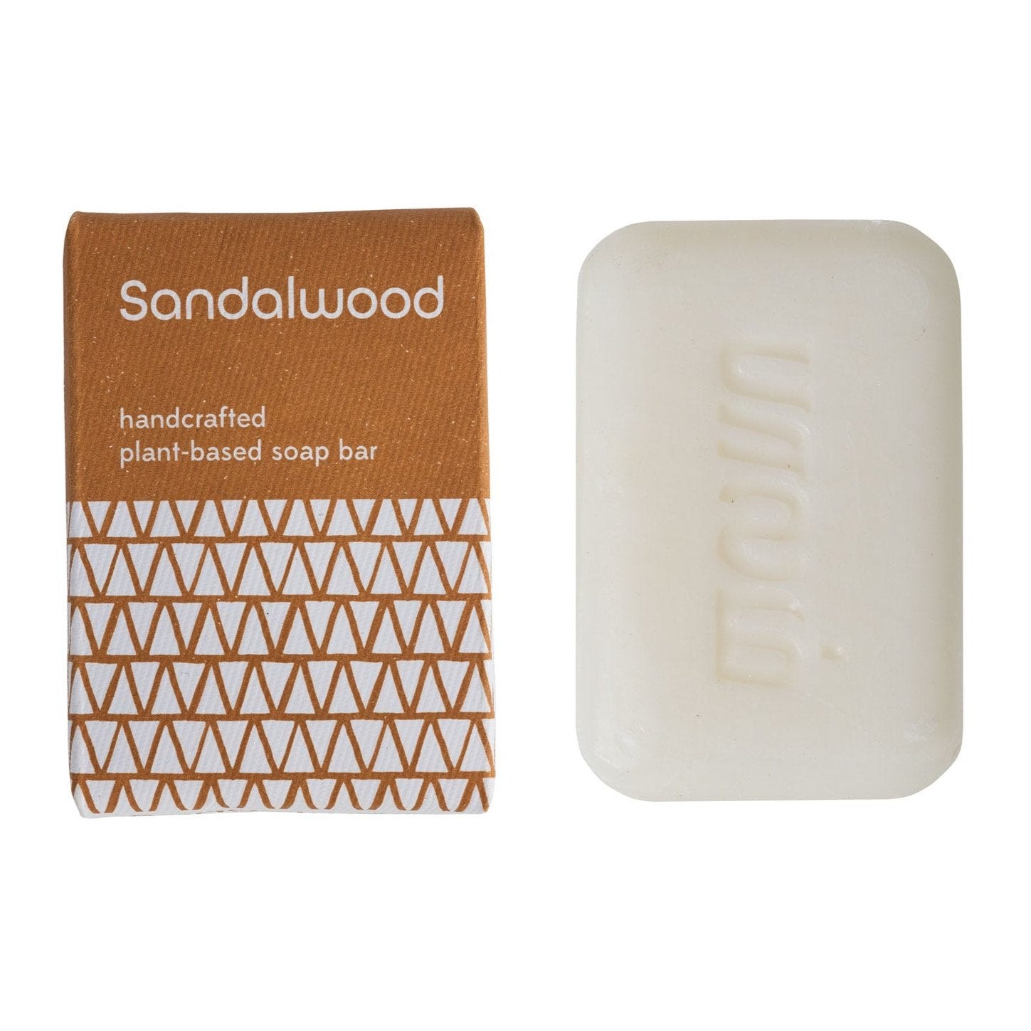 A bar of handcrafted sandalwood soap next to its packaging, which has a geometric pattern in brown and white.