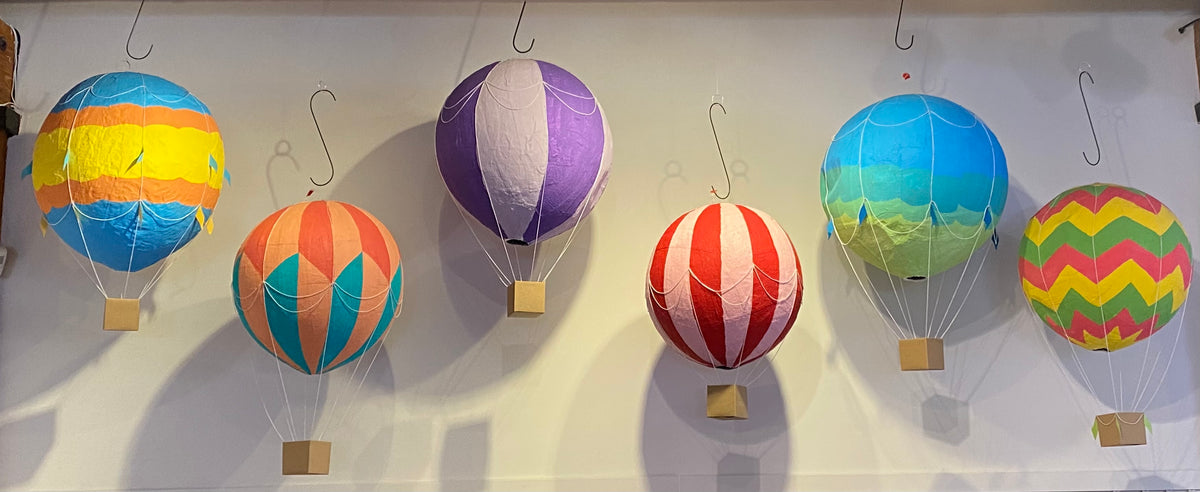 Six plaster of paris hot air balloons in varying colors and patterns.