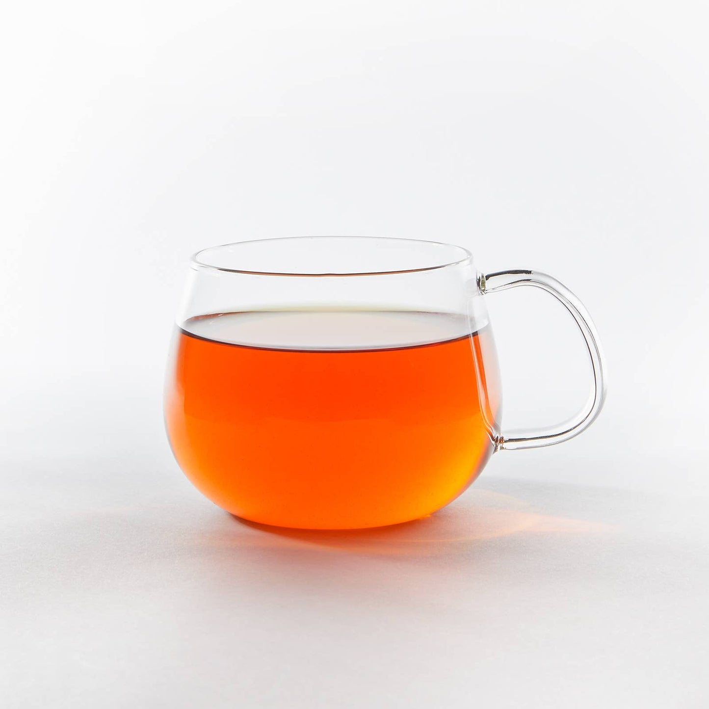 Clear glass mug filled with orange liquid on a white background
