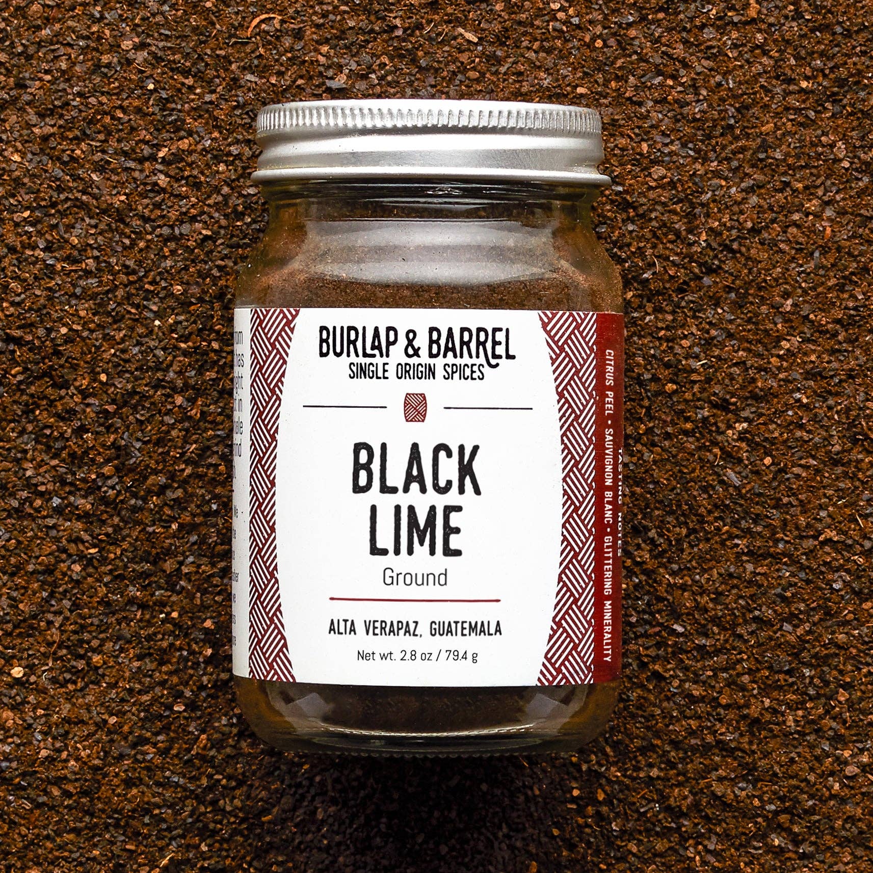 Jar of 'Black Lime' ground spice from Burlap & Barrel on a textured brown background