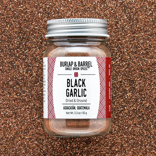 Jar of Burlap & Barrel Black Garlic on a textured brown background