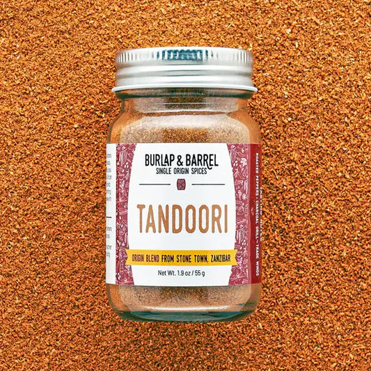 Jar of Burlap & Barrel Tandoori spice blend on a textured orange background