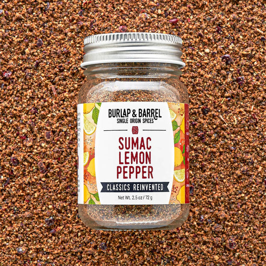 Jar of Burlap & Barrel Sumac Lemon Pepper spice blend on a textured brown background