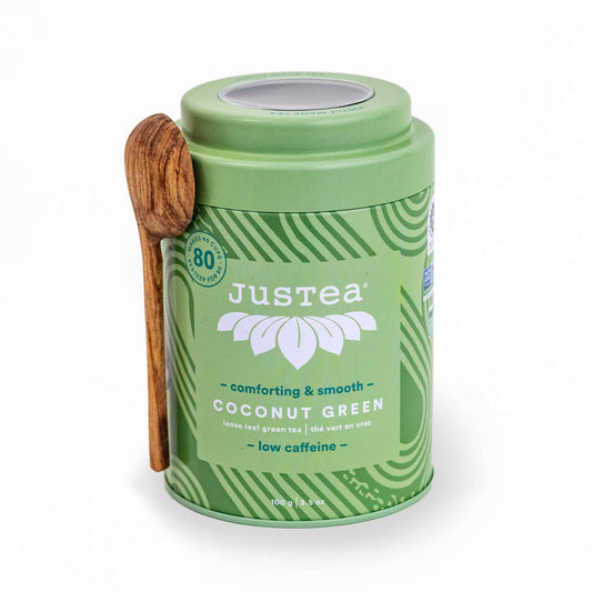 Green Justea coconut green tea canister with a wooden spoon on a white background