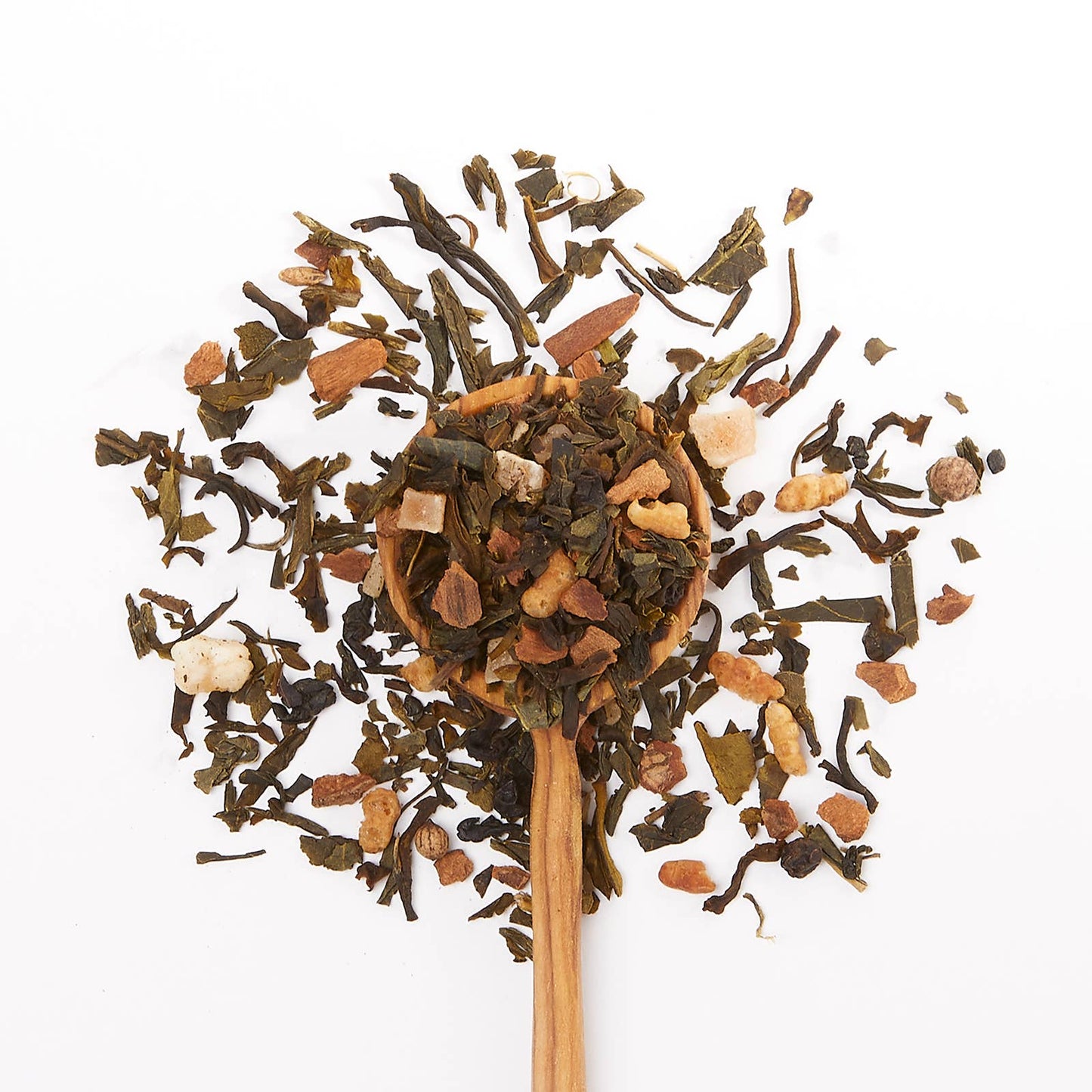 Wooden spoon filled with a mix of dried tea leaves on a white background