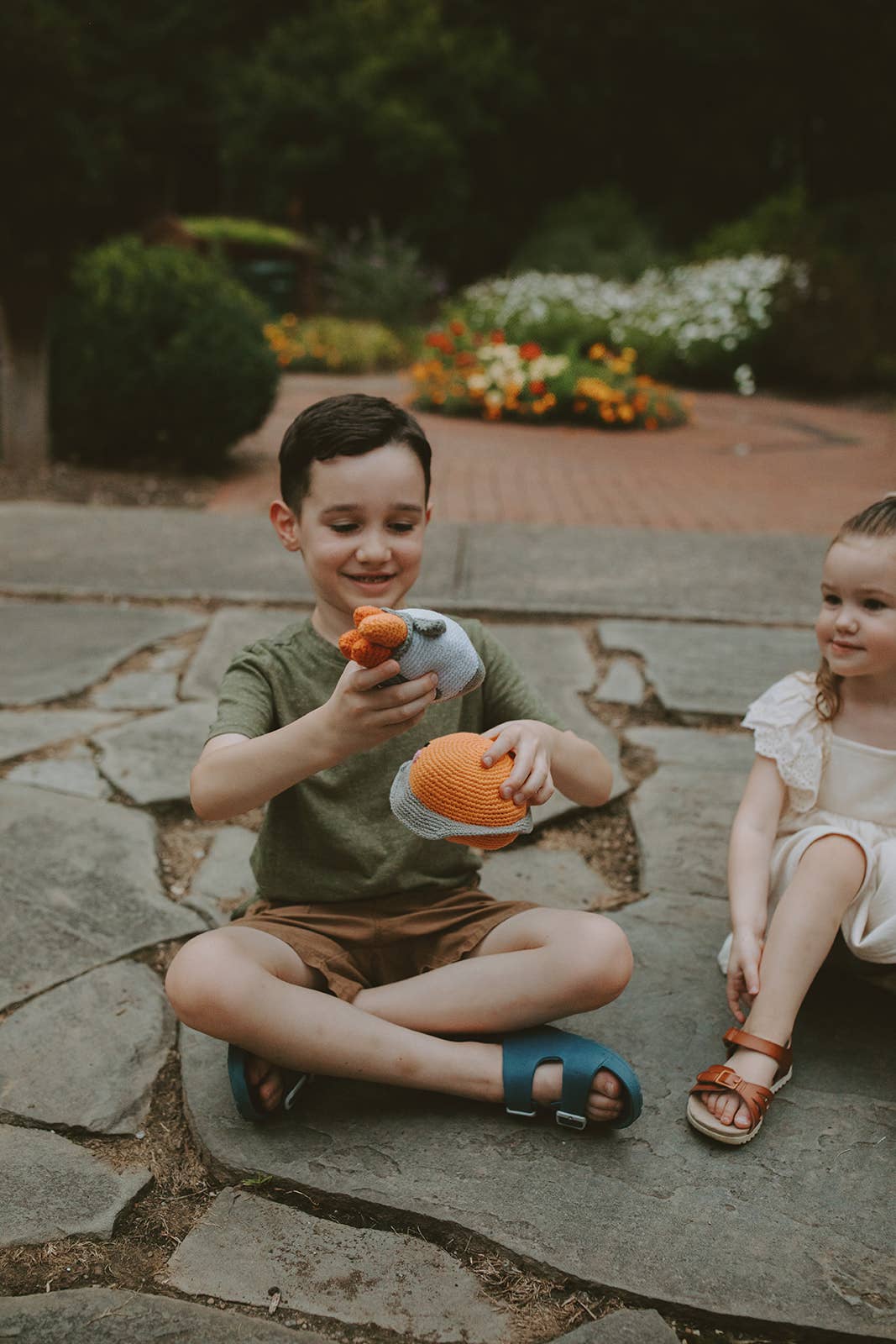 Two children playing with space themed toys on stone tile outdoors.