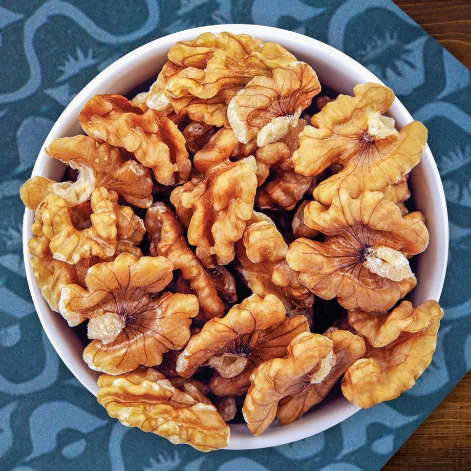 Bowl of raw walnuts on a blue napkin on a wooden table