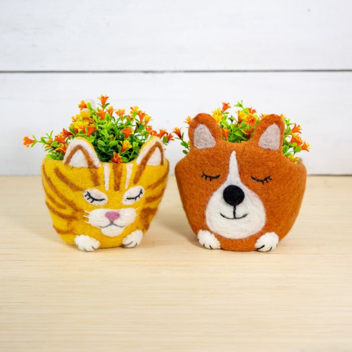Two animal-shaped planters with flowers on a wooden surface
