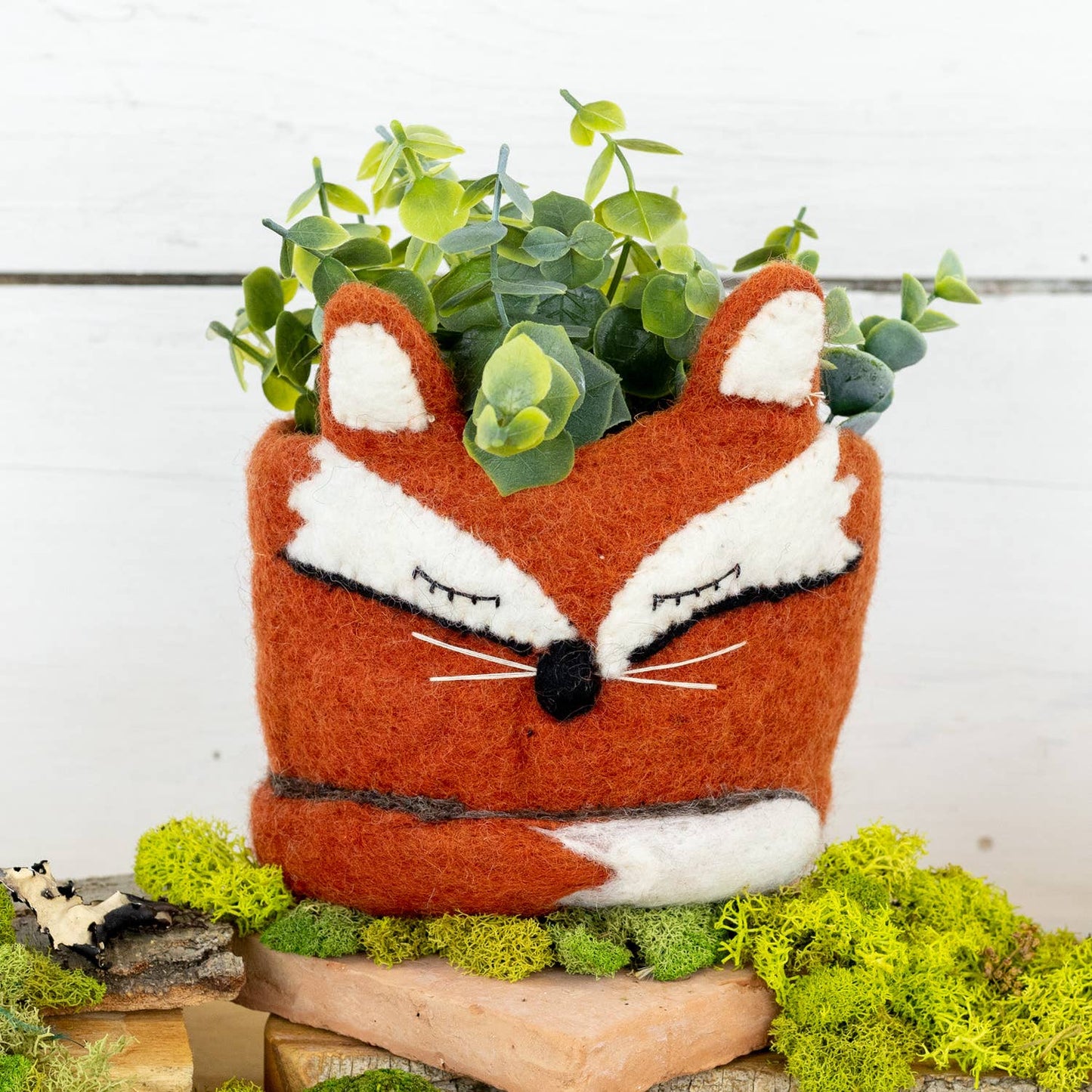 Felt fox planter with greenery on a wooden surface