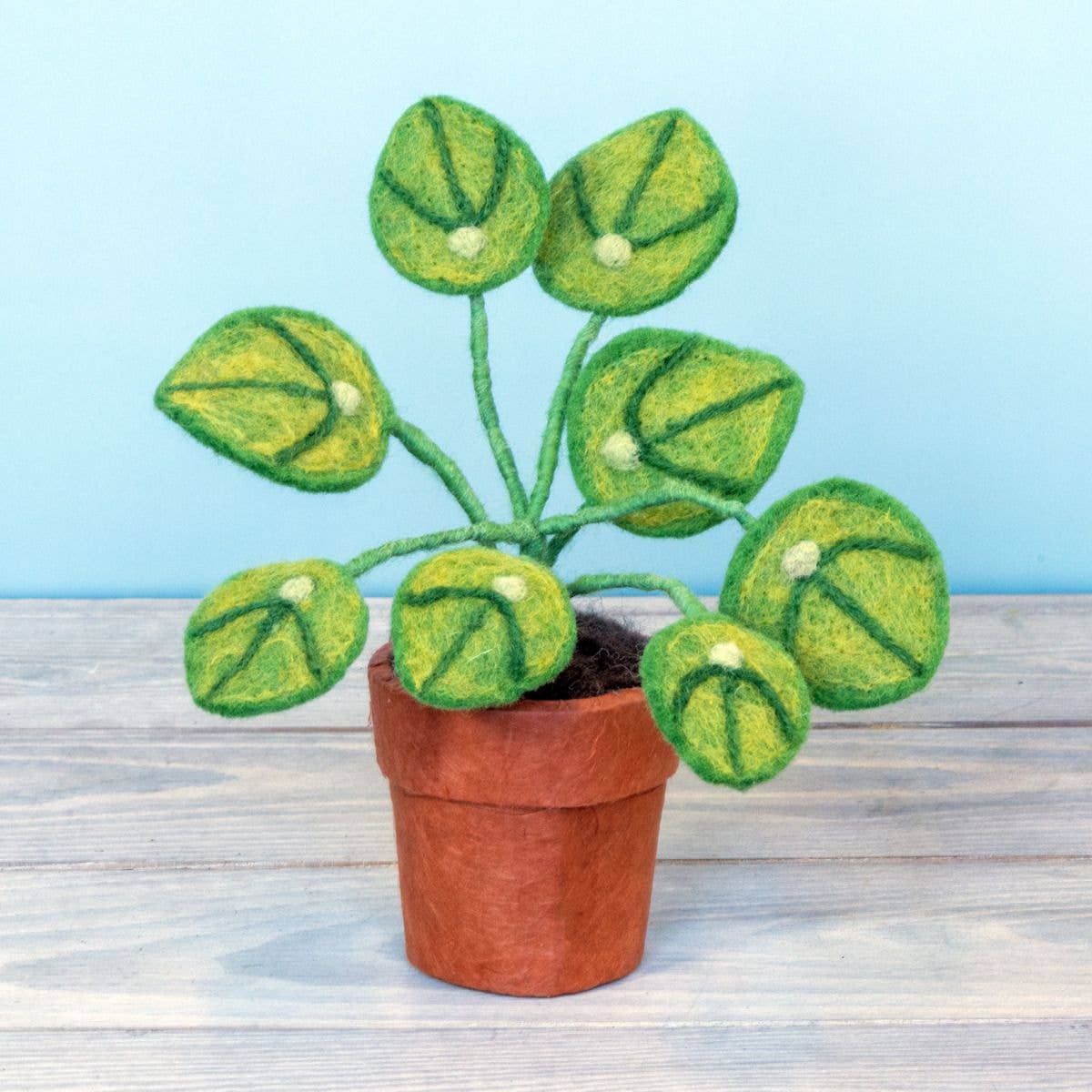 Felted potted plant on a wooden surface with a light blue background