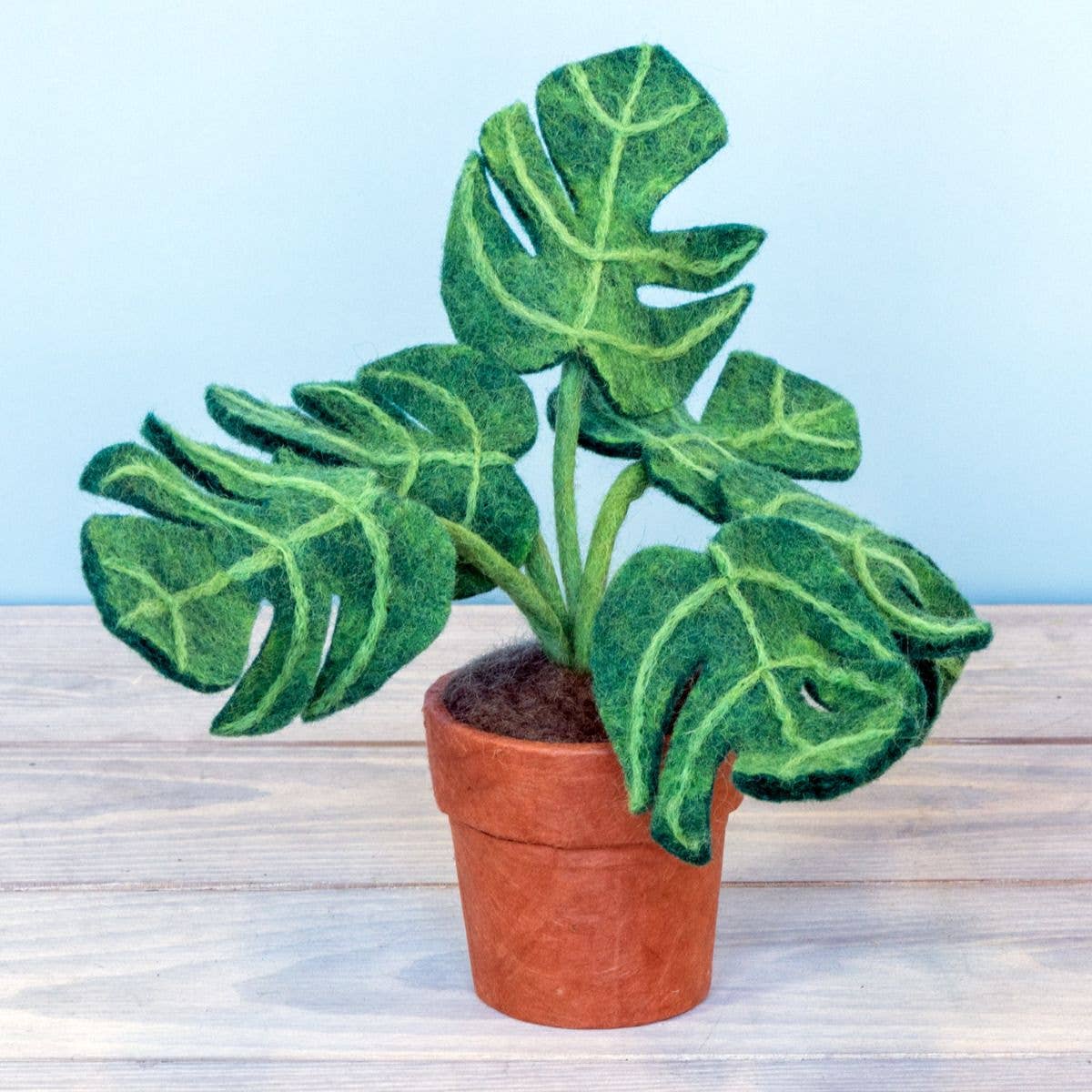 Felt potted plant on a wooden surface with a light blue background