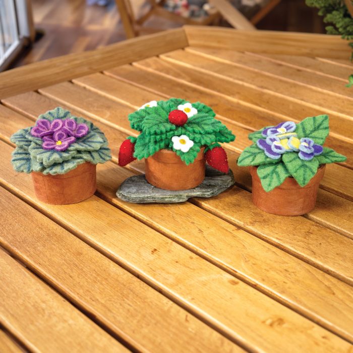 Three felted flower pots on a wooden surface