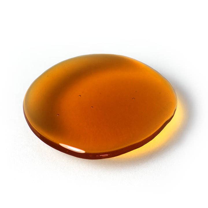 Amber-colored honey drop on a white background