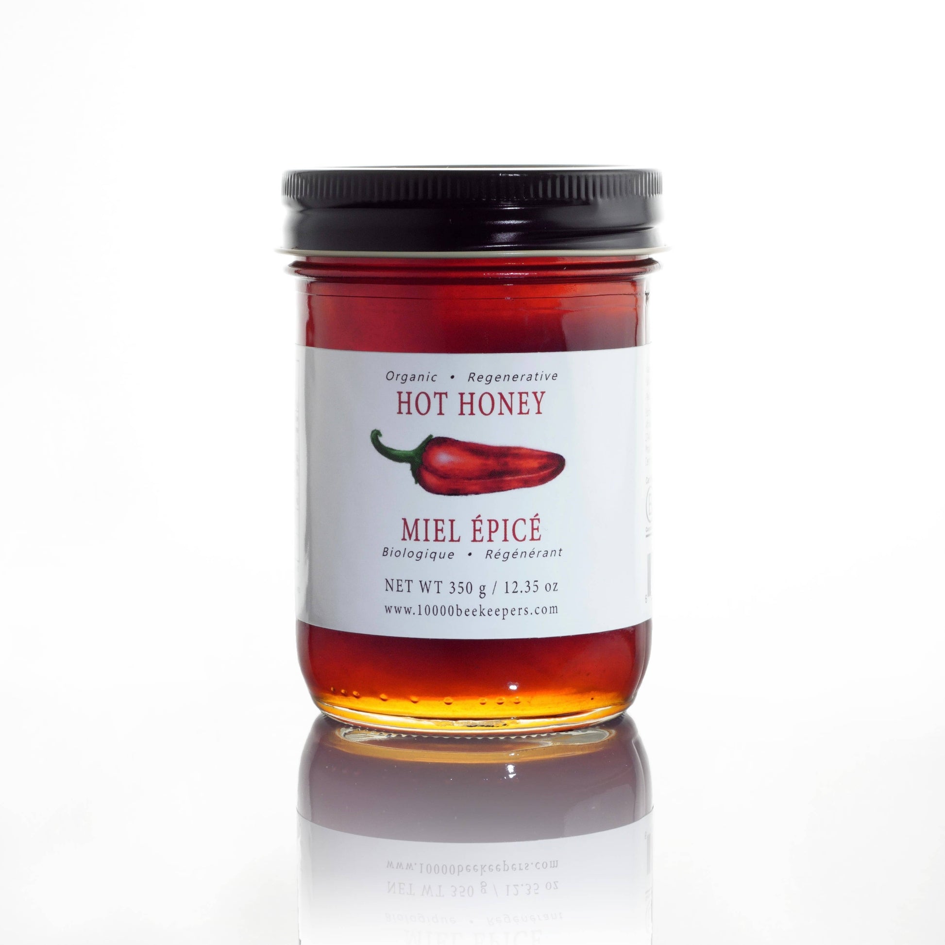 Jar of hot honey with a label featuring a red chili pepper on a white background
