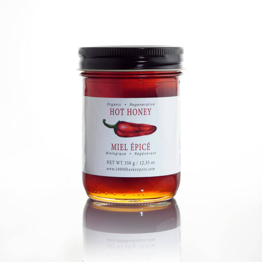 Jar of hot honey with a label featuring a red chili pepper on a white background
