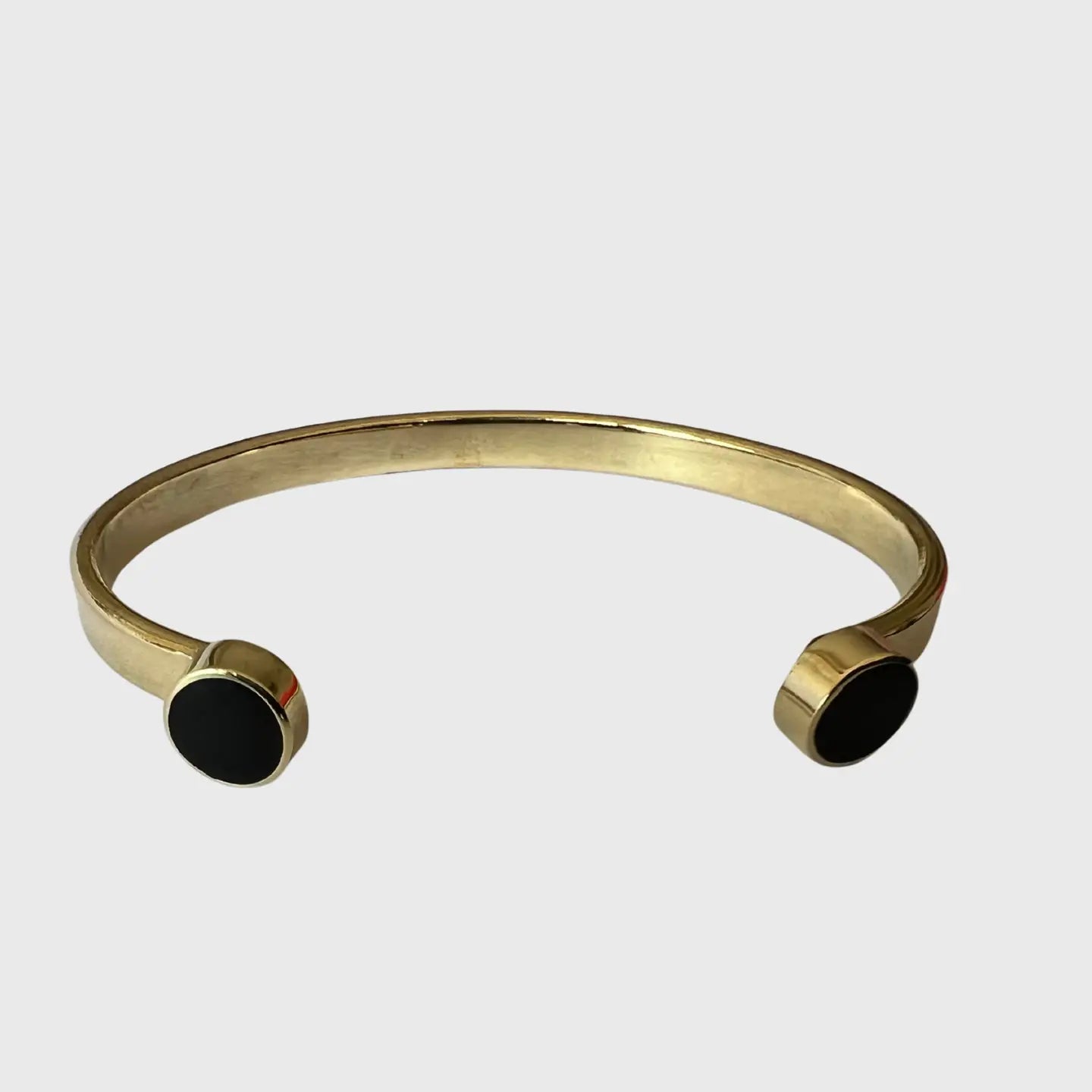 Gold bracelet with black stones on a light gray background