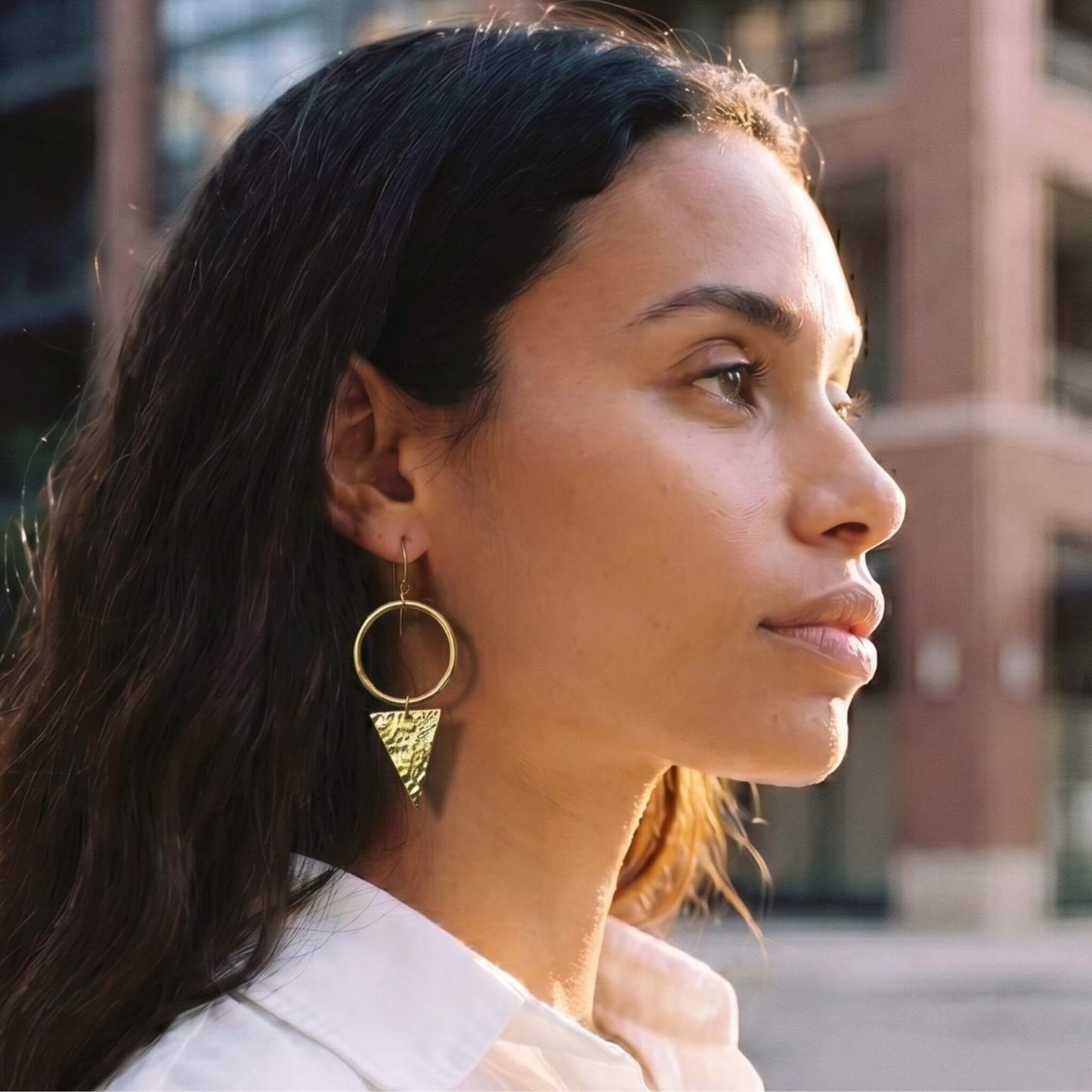 Woman wearing gold hoop earrings with a blurred background