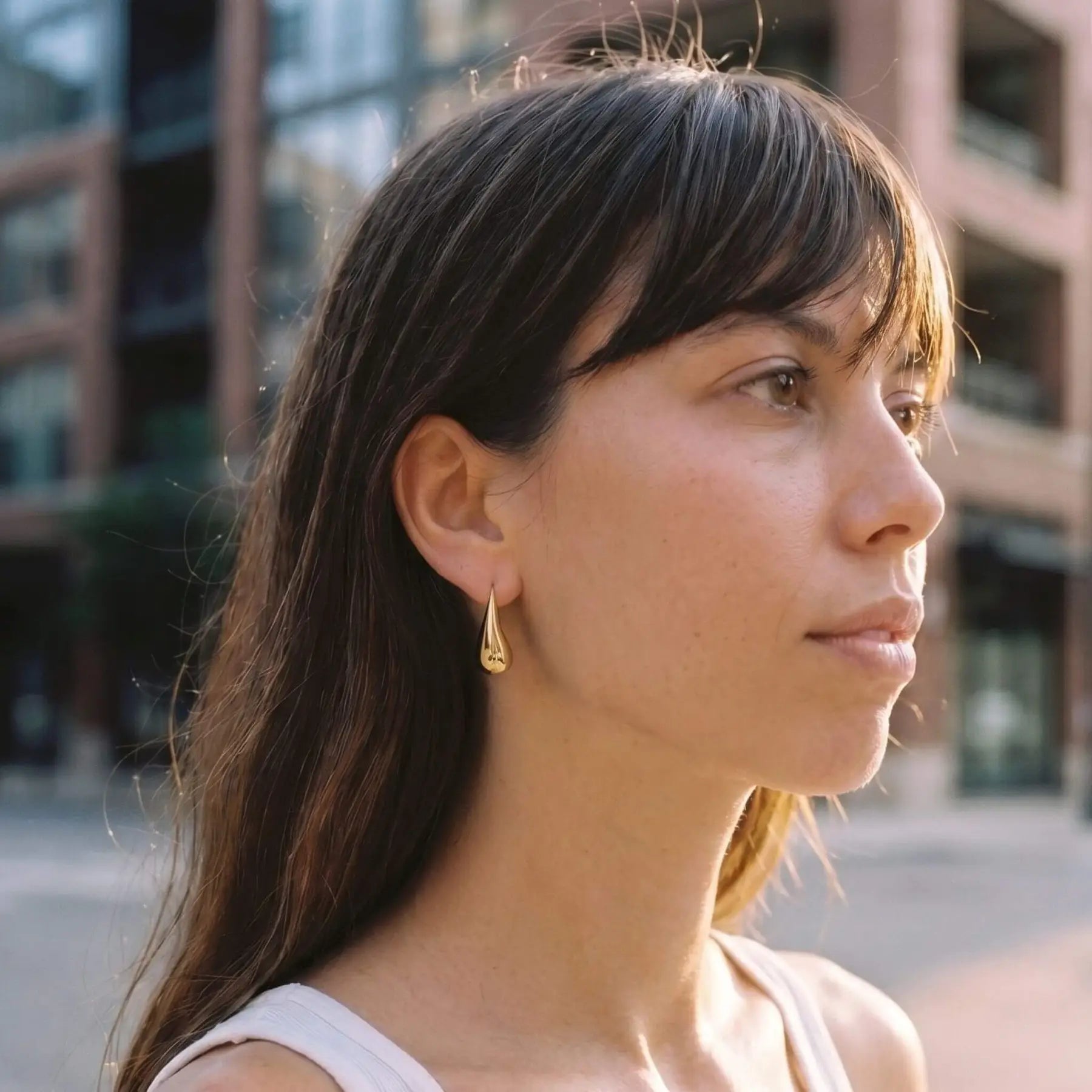 Woman wearing gold teardrop earrings with a blurred background