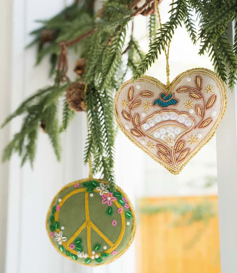 Close-up of a handcrafted floral heart ornament embellished with glass beads, metallic sequins and a blue bird design.