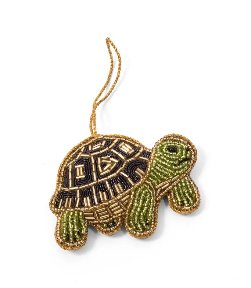 Close-up of a handcrafted green turtle ornament featuring intricate glass beadwork and a patterned black and gold shell.