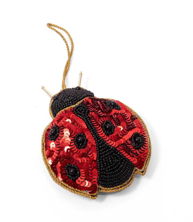 Close-up of a handcrafted ladybug ornament featuring red sequined wings, black beaded spots and gold trim.