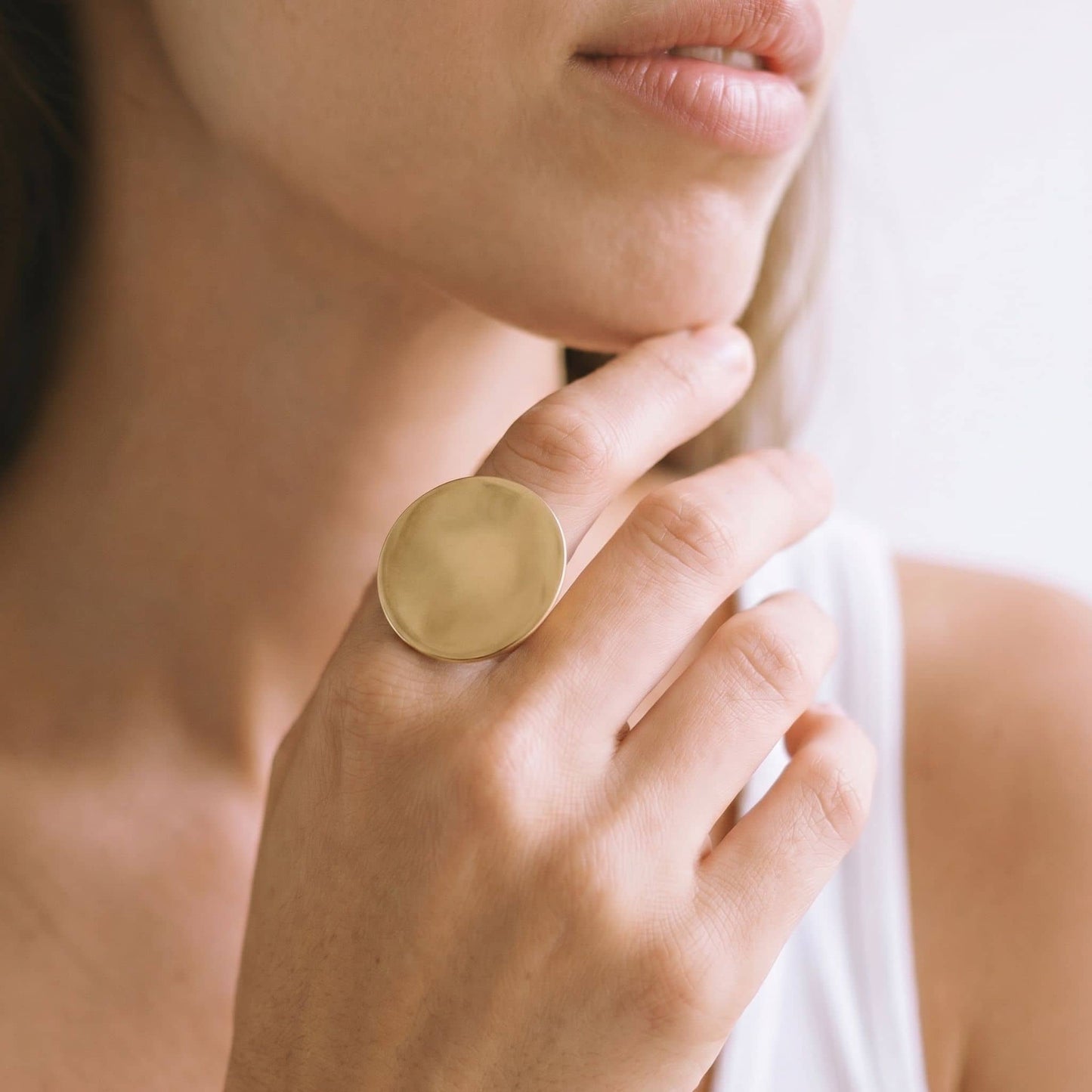 Close-up of a person wearing a gold ring on a blurred background