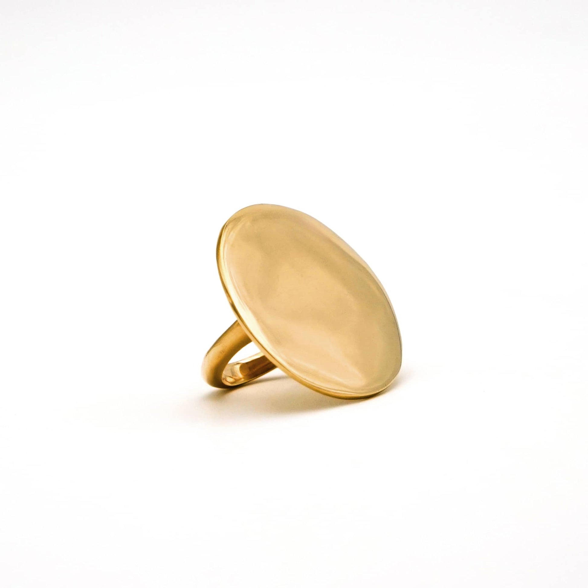 Gold ring with a flat, oval-shaped top on a white background