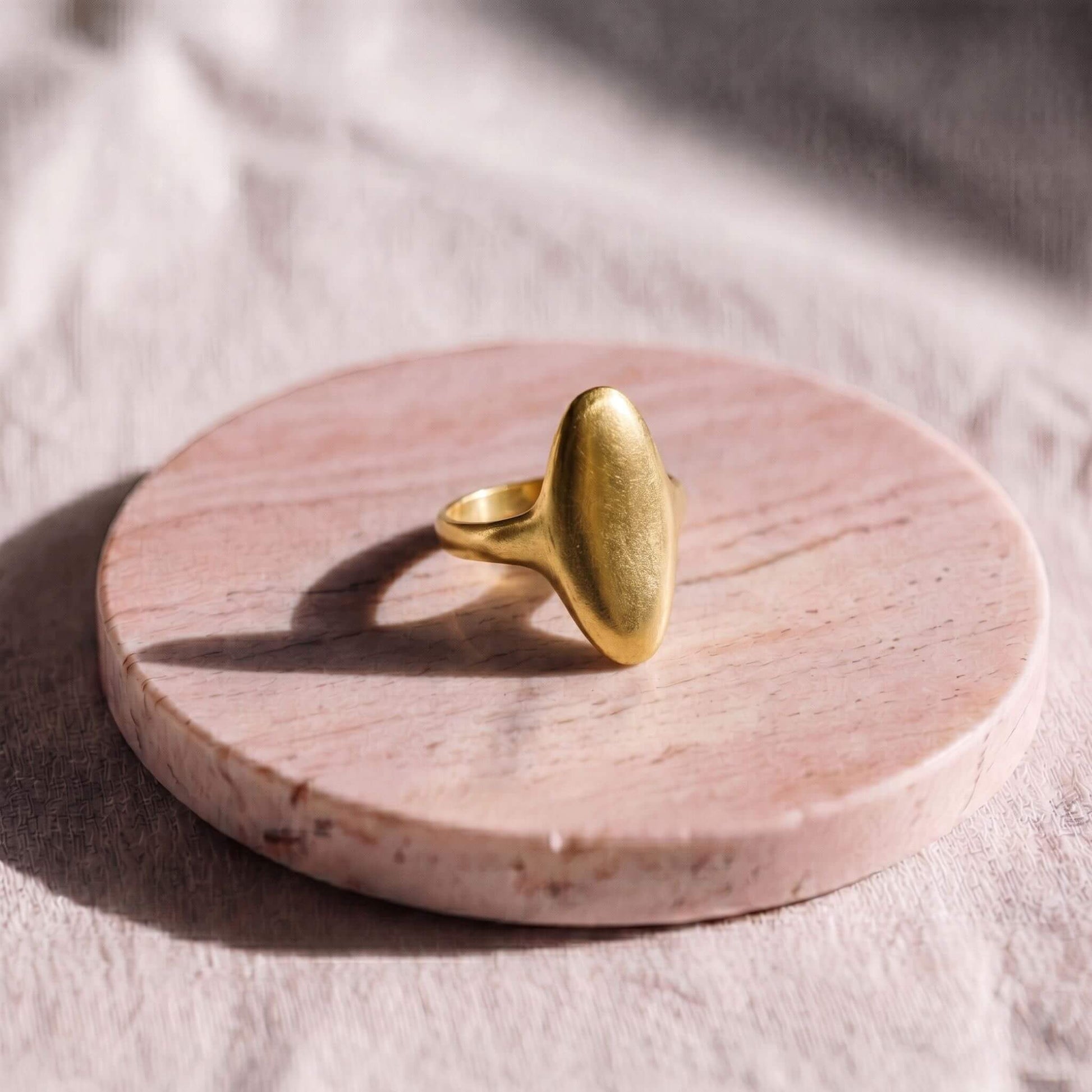 Gold ring on a pink marble coaster with a soft background