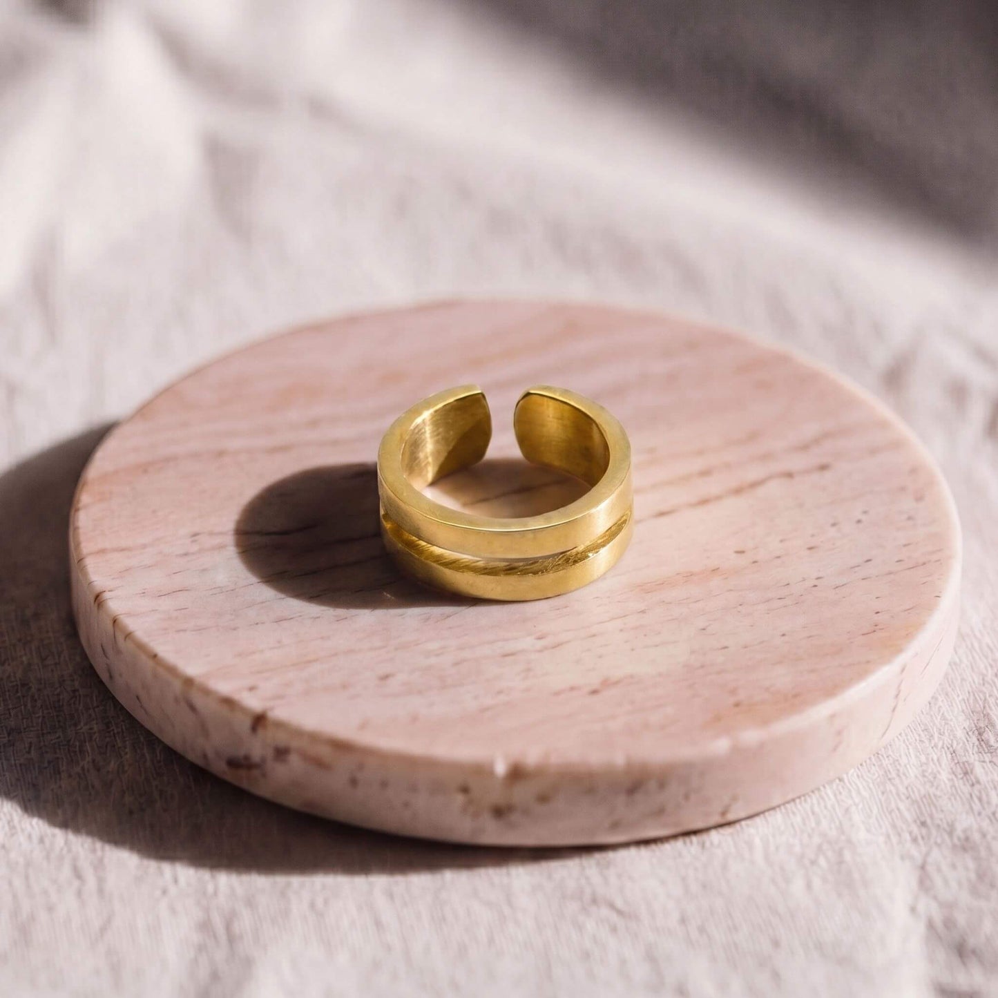 Gold ring on a round pink stone surface with soft lighting