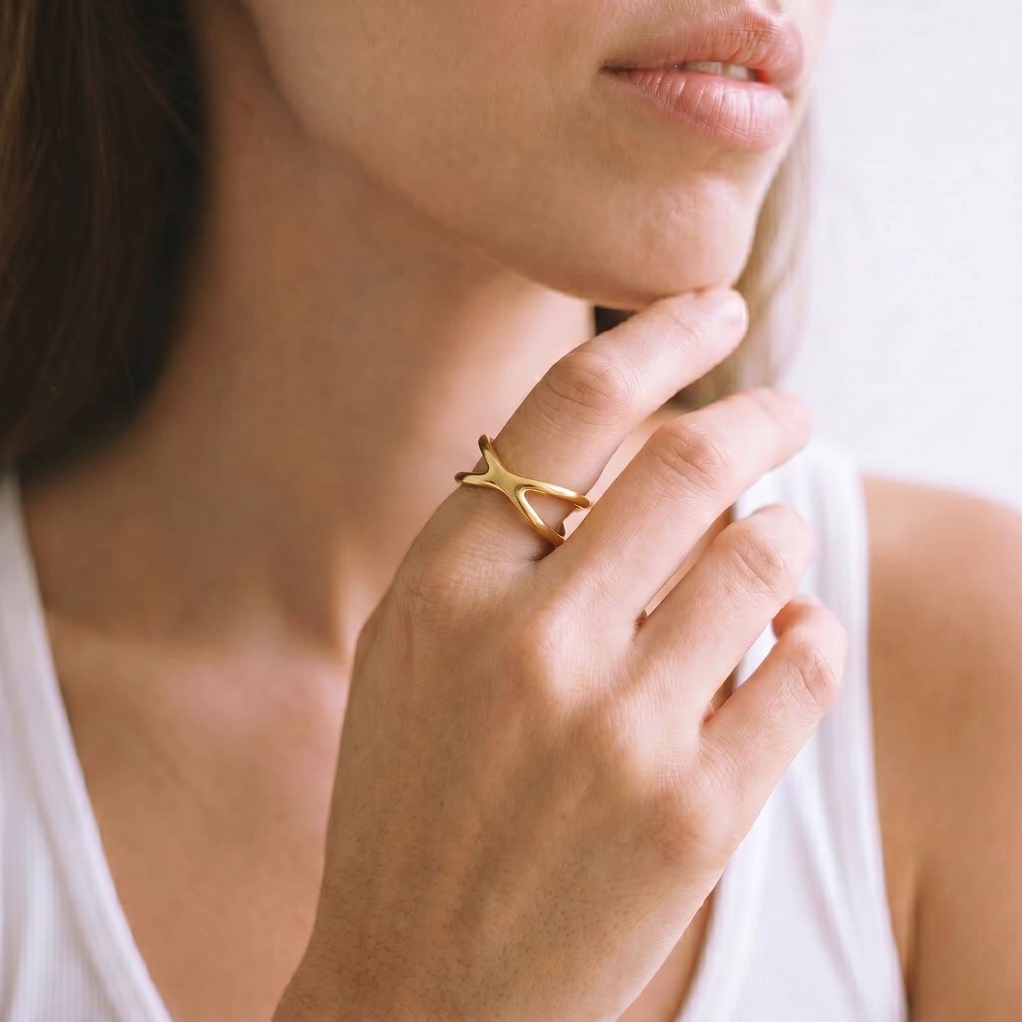 Close-up of a person wearing a gold ring with a white background