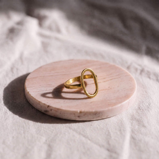 Gold ring on a round wooden platform with a soft white background