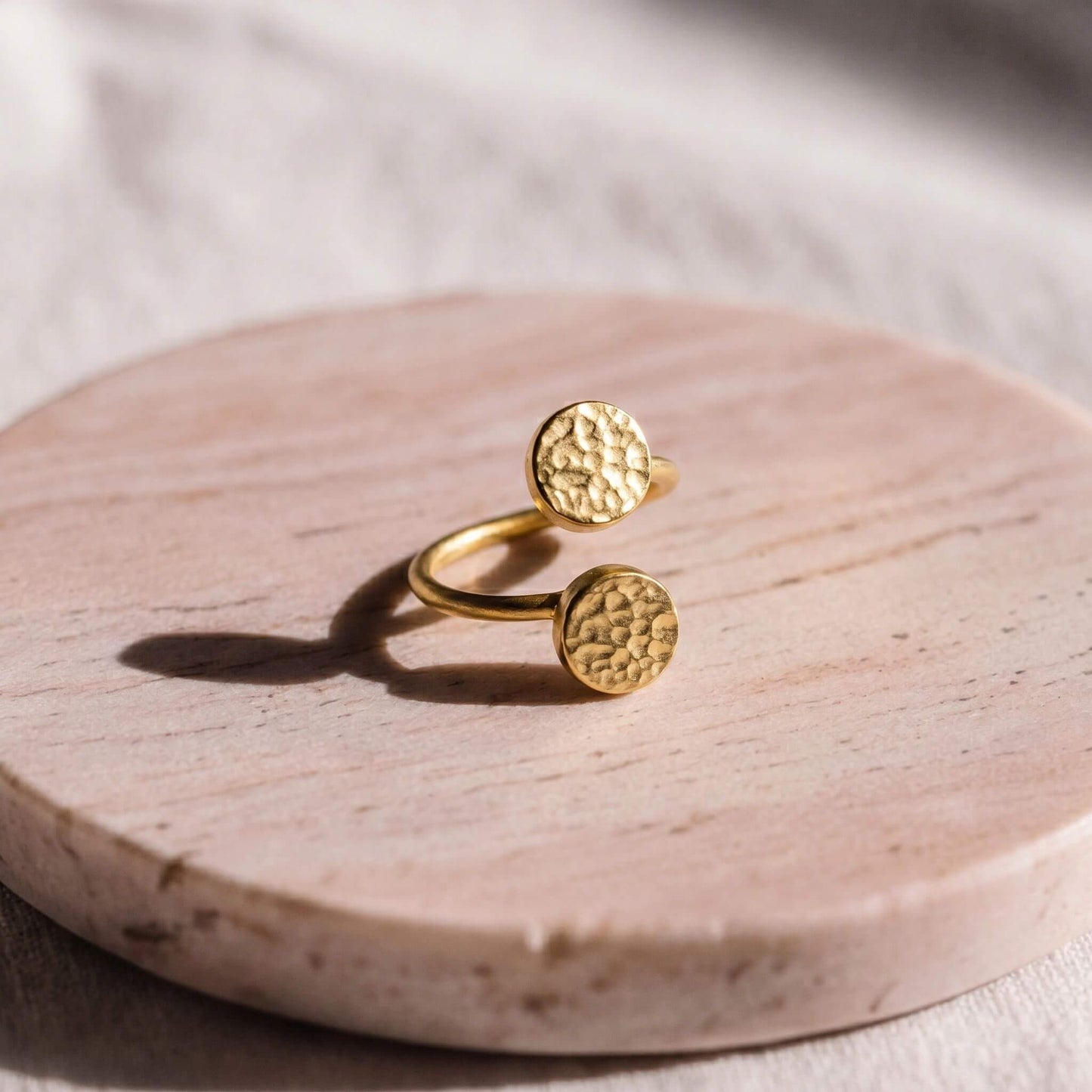 Gold ring with textured circular designs on a wooden surface
