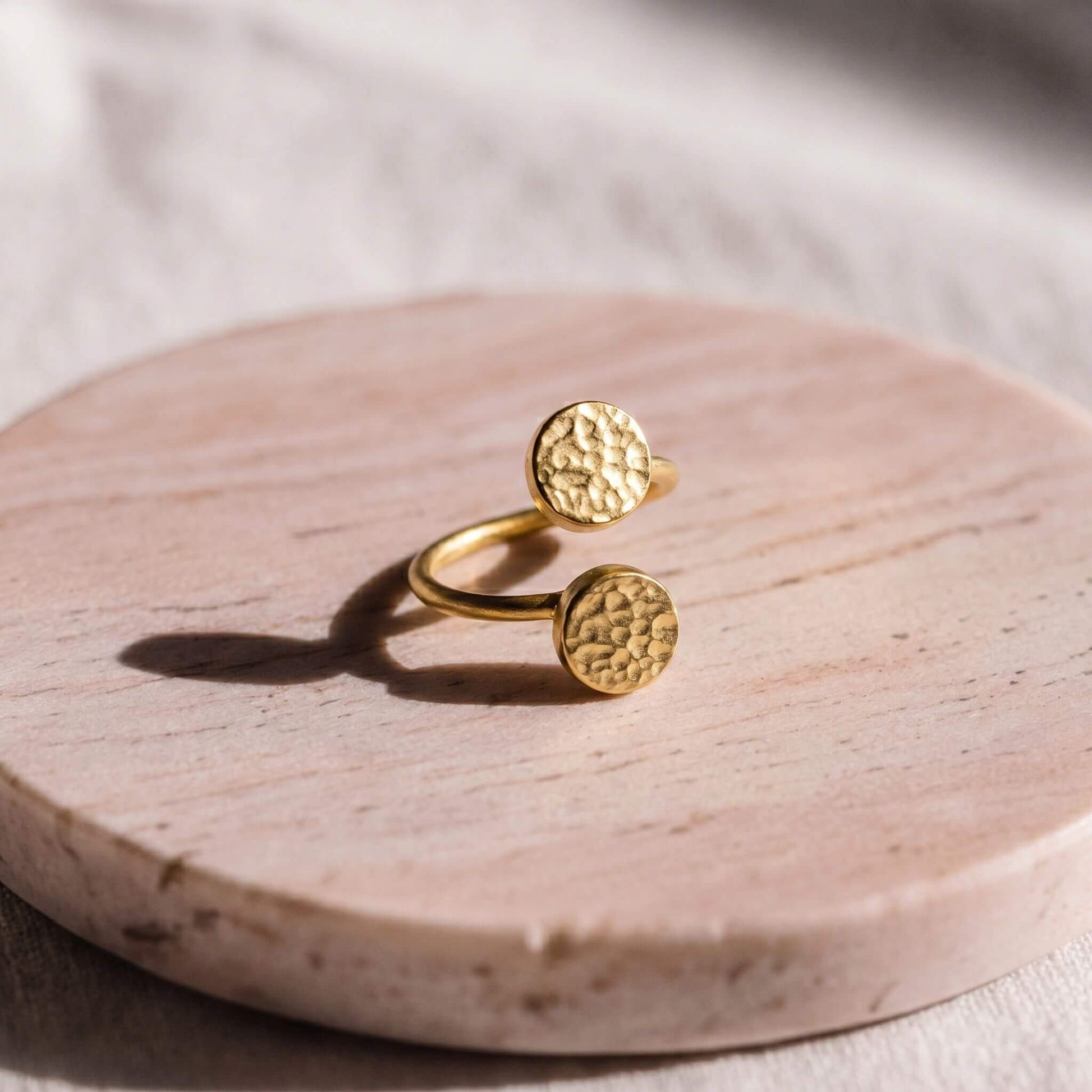 Gold ring with textured circular designs on a wooden surface