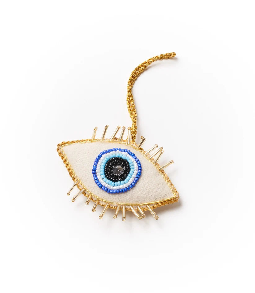 Colorful evil eye ornament featuring blue, white and gold beadwork with intricate embroidered details and a hanging cord.