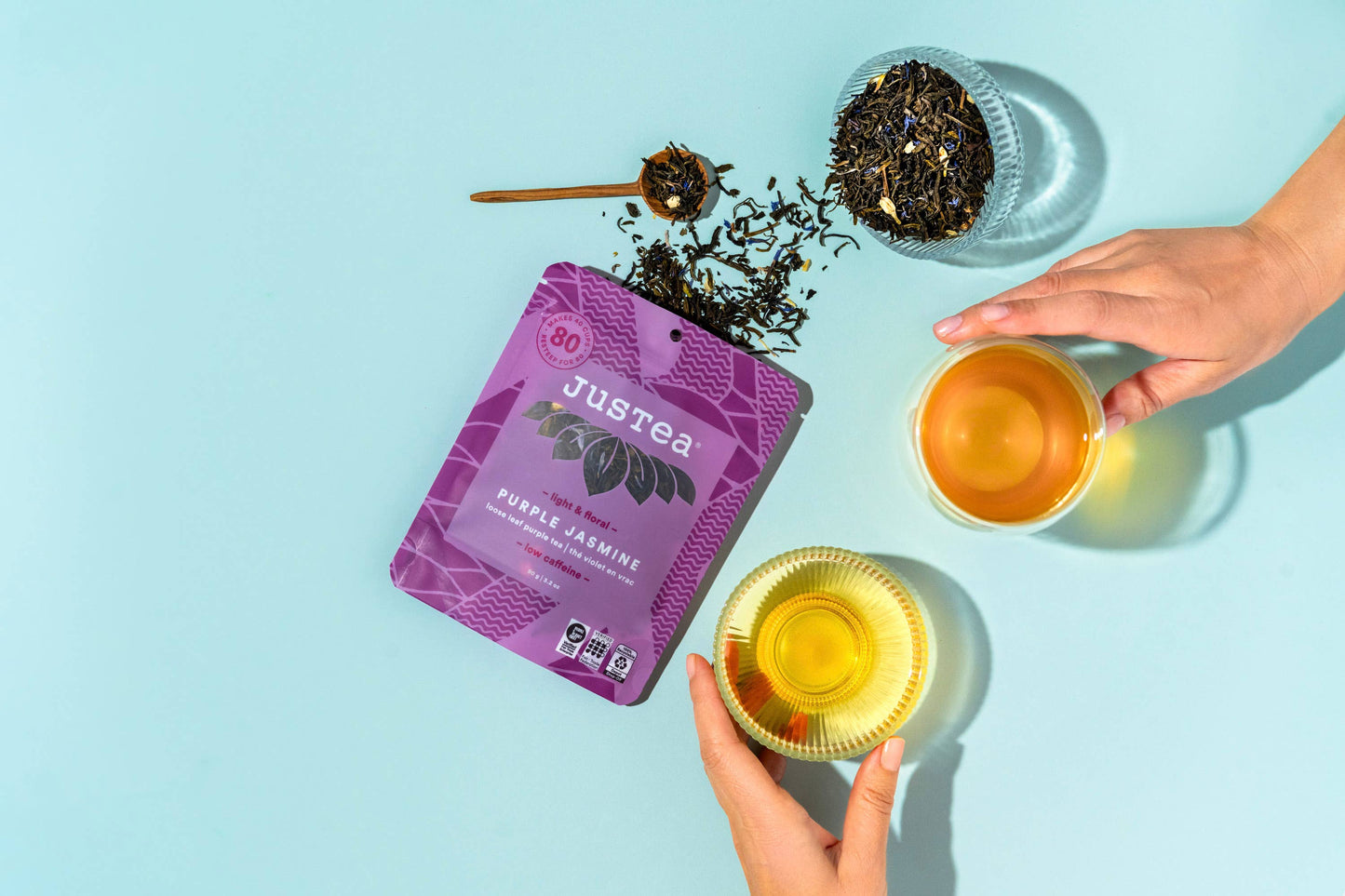 Justea tea packaging with two cups of tea on a light blue background