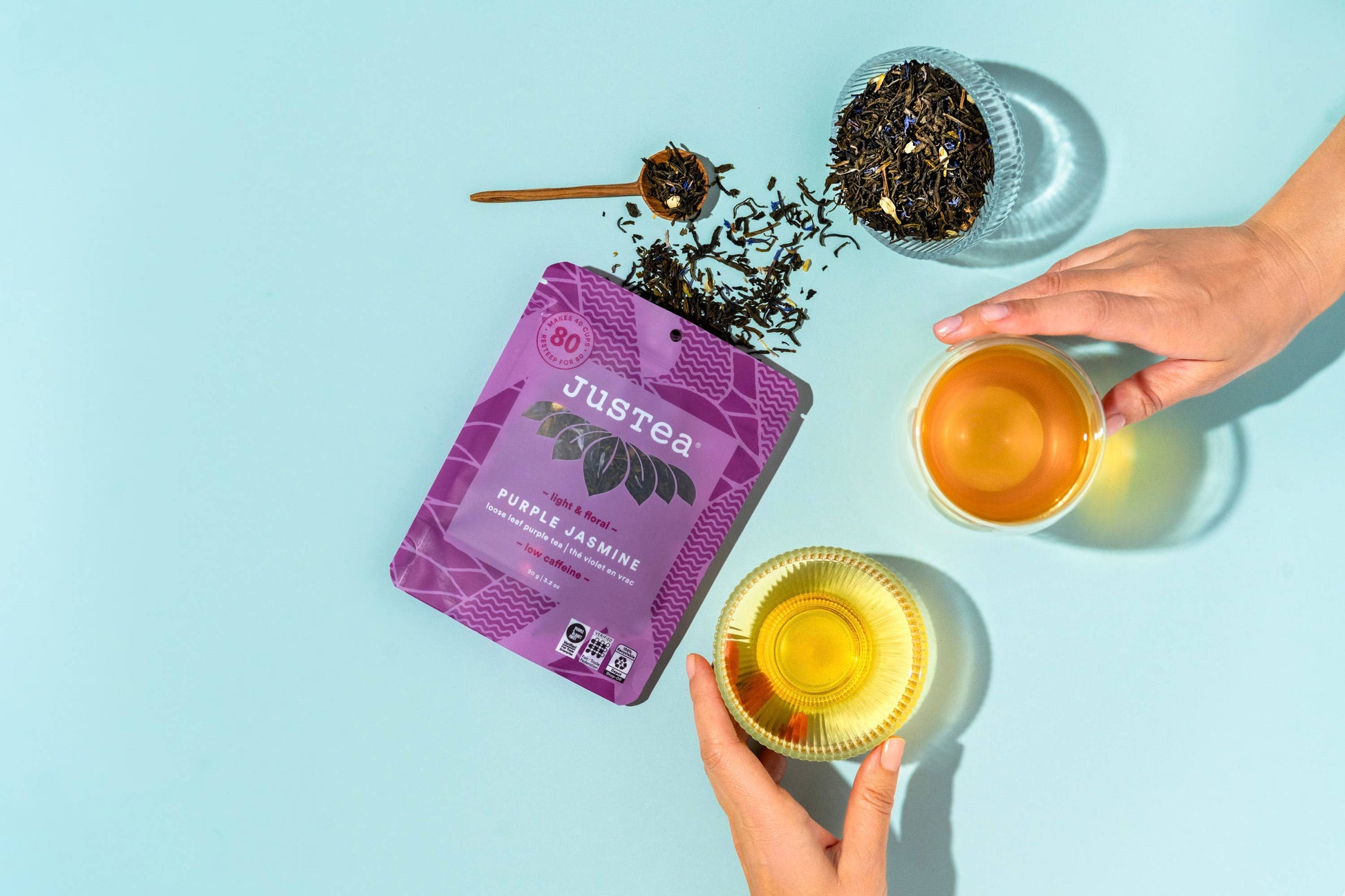 Justea tea packaging with two cups of tea on a light blue background