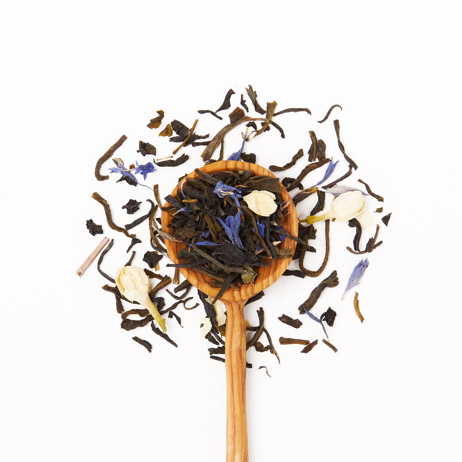 Wooden spoon filled with assorted dried tea leaves on a white background