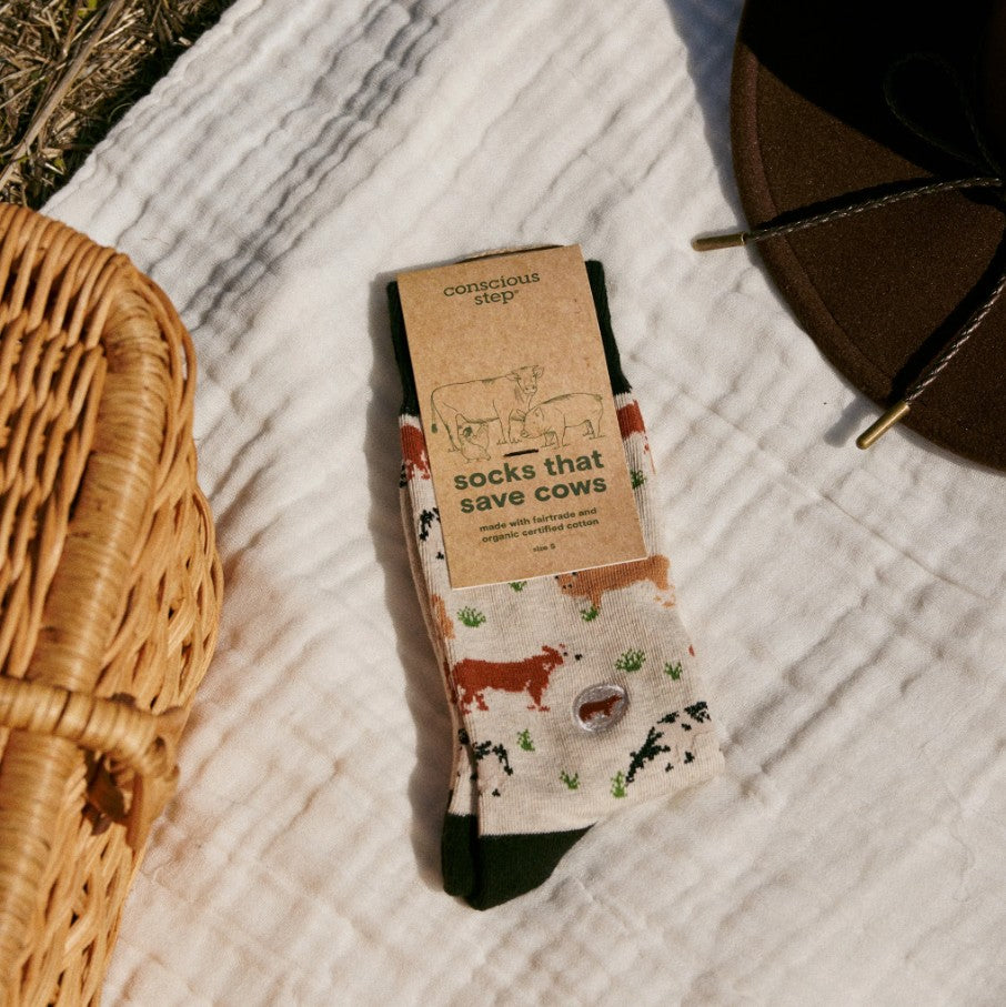 Pair of socks with cow and packaging on a textured surface