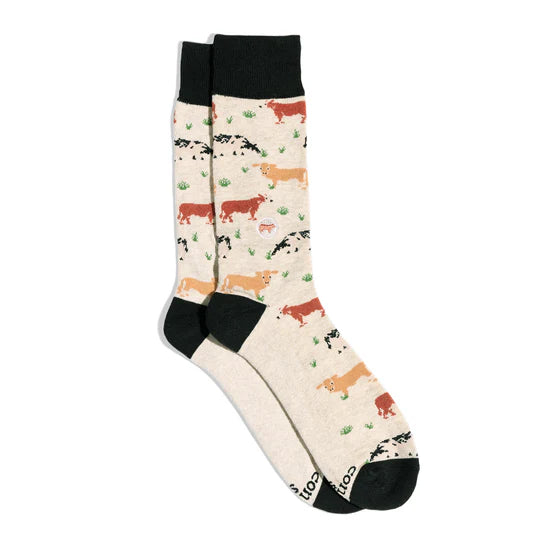 A pair of cream-colored socks with a cow print pattern and black accents.