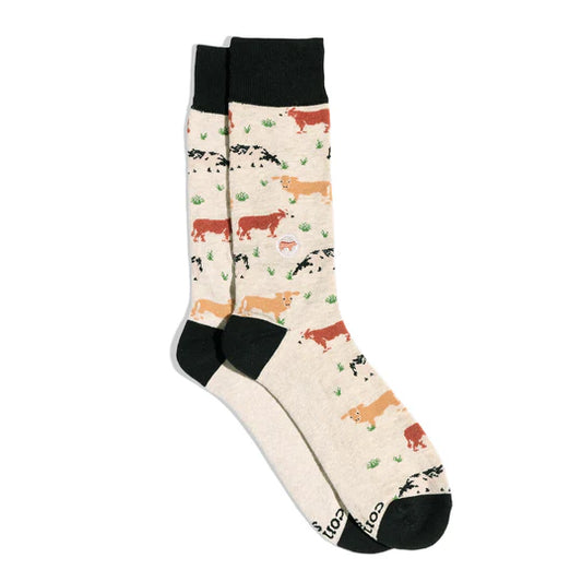 A pair of cream-colored socks with a cow print pattern and black accents.